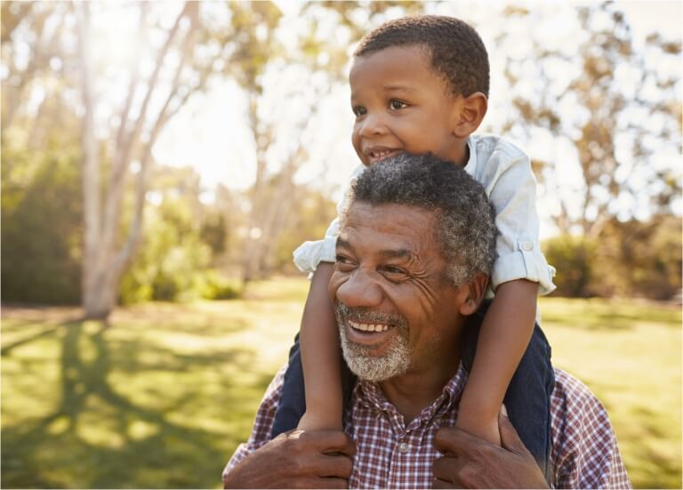 Grandson sitting on grandfather's shoulders